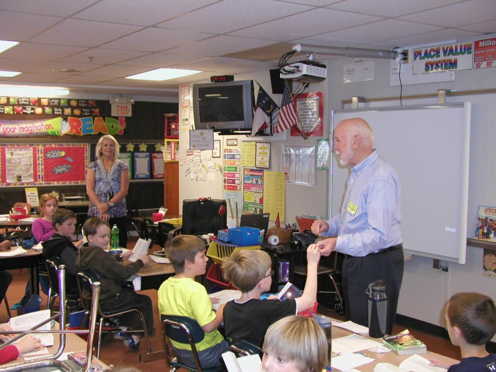 Volunteer presenting dictionaries to students in a classroom